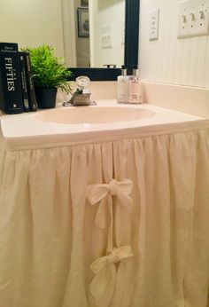 a bathroom sink with a bow on the side and books sitting on top of it