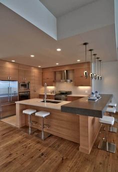 a large kitchen with wooden floors and an island counter top in front of the sink