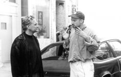 two men standing next to each other in front of a car