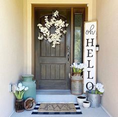 the front door is decorated with white flowers and metal buckets for plants to grow