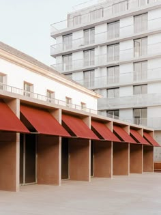 an empty parking lot with red awnings and buildings in the background