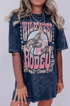 We have the cutest country graphic tees!! Style this tee several different ways such as with boots, shorts, and a bra tuck, or buy it oversized for a t-shirt dress with a rhinestone bodysuit underneath. Features a super soft cotton fabric, crew neck, boyfriend fit (loose in all the right places), black mineral wash base, Ombre graphics "Wild West Rodeo" in a western font, surrounding a bucking cowboy graphic. Fit: Runs true to size, model is wearing a medium. Approximate Measurements: Small- Bus Graphic Tee Cowgirl Outfit, Western Outfits Women Graphic Tee, Graphic Tshirt Dress Outfit Western, Western Graphic Tees Outfit Winter, Western Graphic Tee Dress, Rodeo Inspo Outfits, Rodeo Western Outfits, Graphic Tee Western Outfit, Western T Shirt Outfit