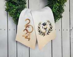 two towels with numbers and wreaths on them hanging from the side of a wooden fence