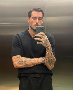 a man with tattoos taking a selfie in an elevator