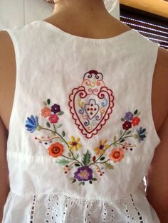 the back of a woman's white blouse with colorful flowers and hearts on it