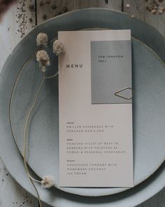 a plate with a menu on it next to some dried flowers and plants in the background