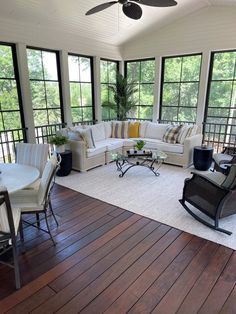 a living room filled with lots of furniture next to large windows on top of a wooden floor