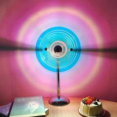 a table topped with a cake next to a blue light lamp on top of a wooden table