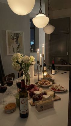 a table topped with plates and bottles of wine next to two candles on top of a counter