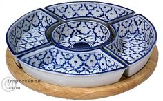 a blue and white serving dish on a wooden stand with two bowls in the center