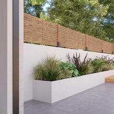 a white planter filled with lots of plants next to a wooden fence and bench