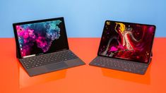 two laptops side by side on an orange and blue surface with the same keyboard