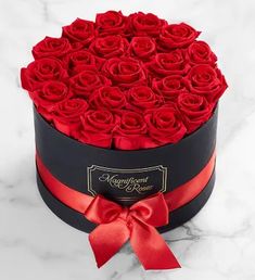 a black box with red roses in it on a marble countertop and the lid is open