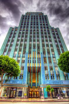 a very tall building with many windows on the front and sides, under a cloudy sky