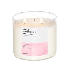 a white candle with pink labels on it