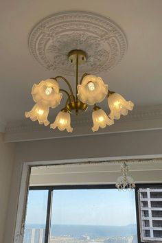 a chandelier hanging from the ceiling in front of a large window with city view