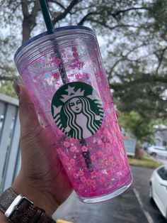 a person holding up a pink starbucks cup with sprinkles on the bottom