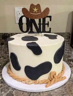 a birthday cake decorated with black and white cow print