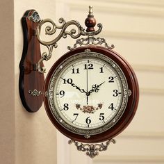 a clock hanging from the side of a wall next to a doorway with an ornate frame