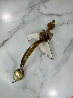 a marble counter top with a metal handle on it's end and a gold plated object in the middle