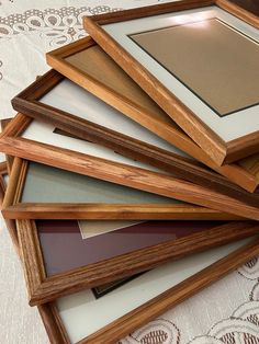 a pile of wooden frames sitting on top of a white lace covered table cloth,