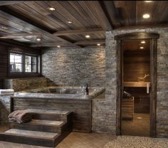 a bathroom with stone walls and steps leading up to the jacuzzi bathtub