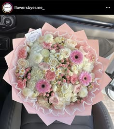 a bouquet of pink and white flowers sitting in the back seat of a car,