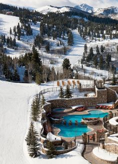 an aerial view of a ski resort with a pool in the foreground and mountains in the background