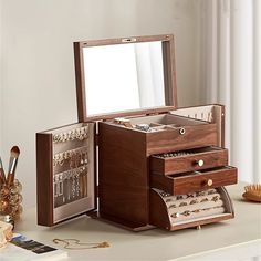 an open jewelry box on a table next to a mirror and other items in front of it