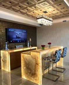 a bar with chairs and a television mounted on the wall in a room that has tile flooring