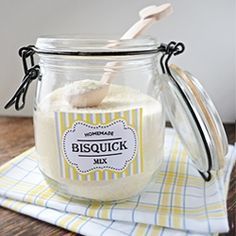 a jar filled with some kind of white substance on top of a wooden table next to a spoon