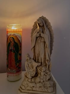 a lit candle next to a statue of the virgin mary