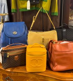 several purses are lined up on top of a wooden table in front of a mirror