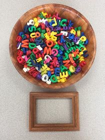 a wooden bowl filled with letters sitting on top of a table next to a frame