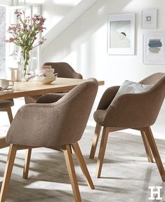 a dining room table and chairs in front of a window with flowers on the table