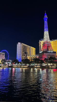 the eiffel tower lit up at night in las vegas, with ferris wheel visible