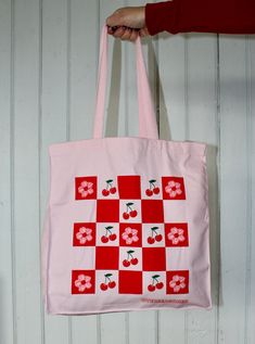 Pack up a picnic in this vibrant pink tote bag, displaying a checkerboard of cherries and cherry blossoms. It's the perfect accessory for spring! Totes are made of 12 oz cotton with self-fabric handles. They're very sturdy, you don't have to worry about overloading or ripping these. They measure a solid 10 inches wide by 13 1/2 inches high and expand to about 5 inches deep. Machine washable, tumble dry, iron as needed, bleach not recommended. Picnic Tote, Pink Tote Bag, Pink Tote Bags, Pack Up, Pink Tote, Foodie Gifts, A Picnic, Food Gifts, Kids Hats