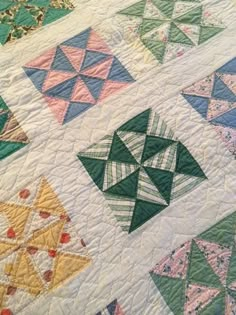 a close up of a quilt on a bed with many different colors and shapes in it