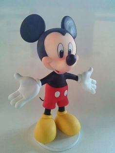 a mickey mouse figurine is posed on a white surface