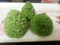 three green cakes sitting on top of a white plate