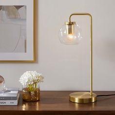 a lamp on a table next to a vase with flowers in it and a book