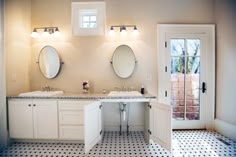 a bathroom with two sinks, mirrors and lights on the wall next to each other