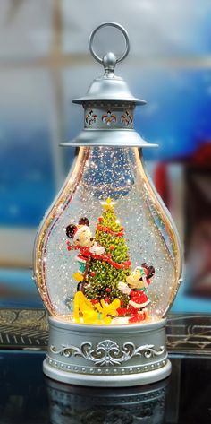 a snow globe with mickey mouse and christmas tree in it's centerpiece on a table