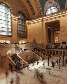 many people are walking around in an old building with large windows on the ceiling and high ceilings