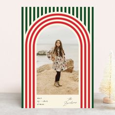 a christmas card with an image of a woman standing on the beach in front of a tree