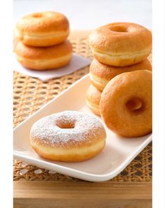 four donuts on a white plate with powdered sugar