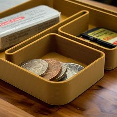 a wooden desk with three compartments holding coins and two small tins on the table