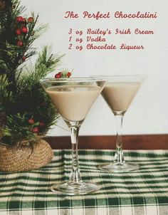 two martini glasses sitting on top of a table next to a potted christmas tree