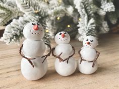 three snowmen standing next to each other in front of a christmas tree