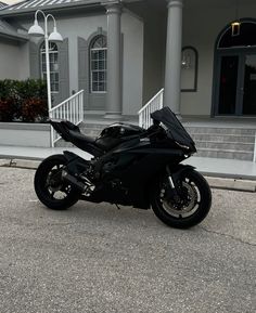 a black motorcycle is parked in front of a large house with steps leading up to it